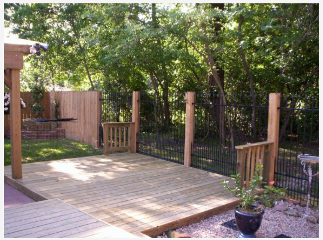 Custom backyard deck built alongside a metal fence by Cavalier Custom Decks in Coldspring, TX
