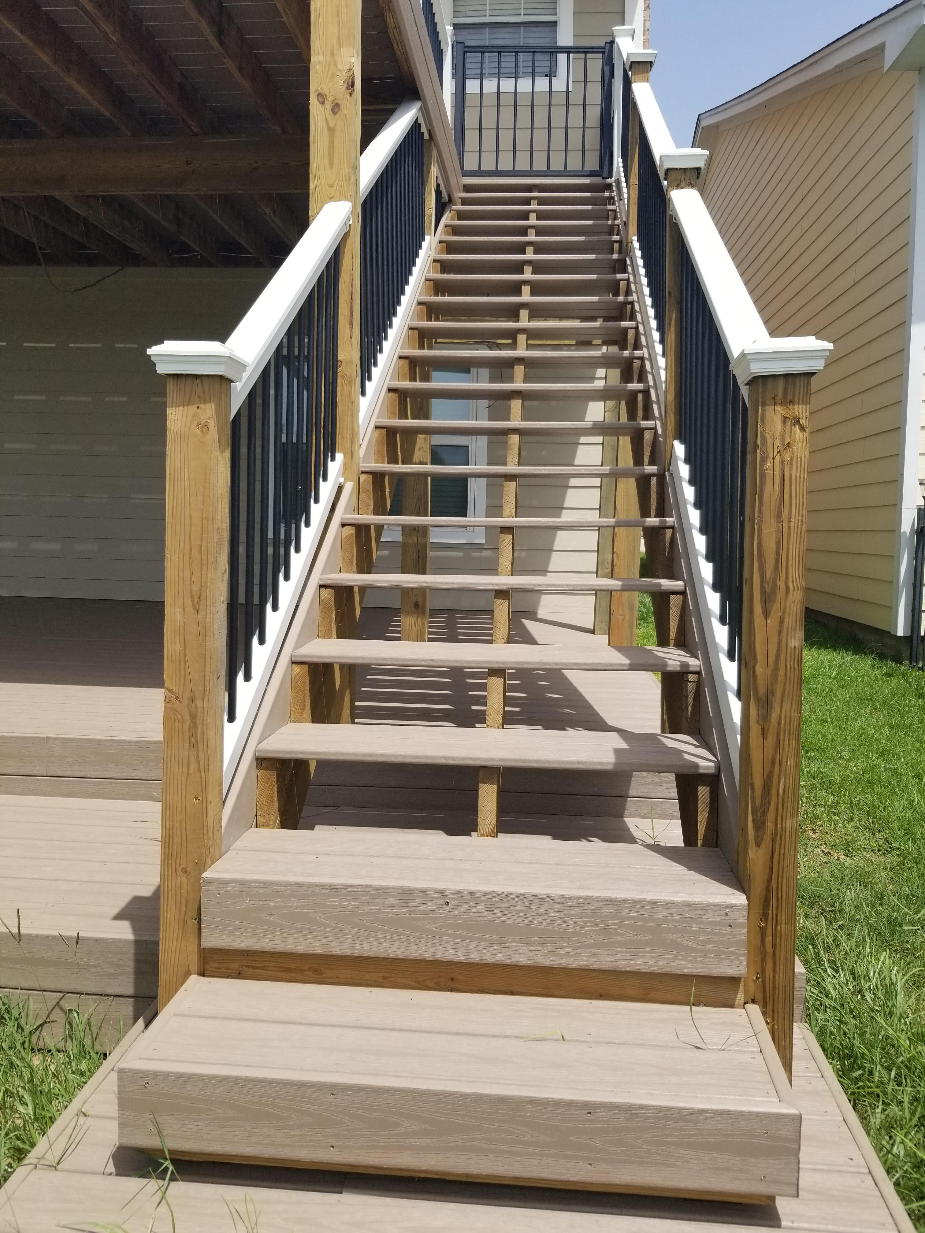 Long composite deck staircase with black metal railing built by Cavalier Custom Decks